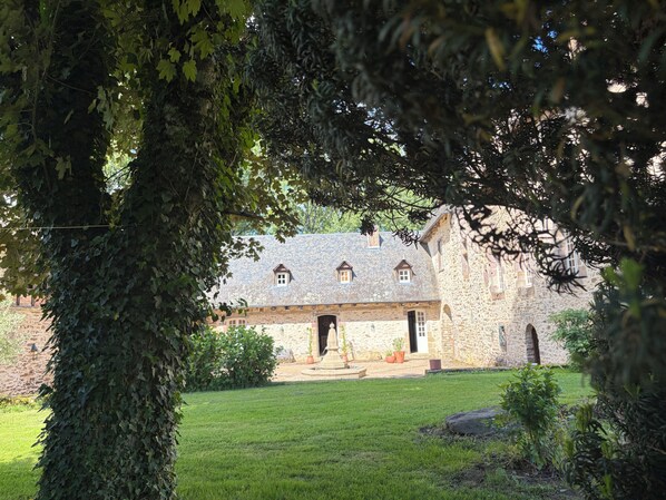 Un bâtiment en pierre, avec un toit en pierre, une entrée centrale et une petite fenêtre au deuxième étage.