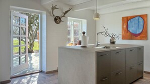 Una cocina moderna con una isla central, un amplio ventanal y una decoración rústica de cabeza de ciervo.