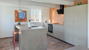 Una cocina moderna con una isla central, estufa y ventana.