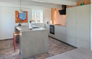 A modern kitchen with a central island, a stove, and a window.
