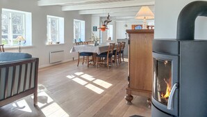 Un salón espacioso con chimenea, suelo de madera y zona de comedor con mesa y sillas.