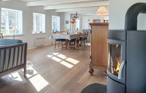 A spacious living room with a fireplace, wooden flooring, and a dining area with a table and chairs.