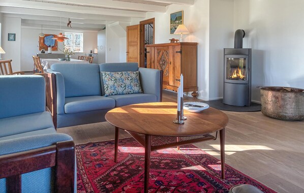 A cozy living room with a blue sofa, a wooden coffee table, and a red patterned rug. A fireplace is visible in the background.
