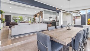 A spacious living area with a large sofa, dining table, and chairs. There is a kitchen area with cabinets and a countertop visible in the background. - Waterfront Ft Lauderdale Retreat | Kayaks Included (Fort Lauderdale)
