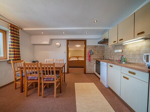 Une cuisine compacte avec des meubles de rangement en bois, une table à manger avec des chaises, un petit évier et un four à micro-ondes.
