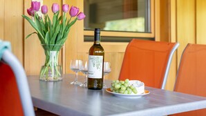 A dining table with a bottle of wine, glasses, a plate of grapes, and a vase of tulips. - Alpine Holiday Apartment with Balcony (Söll)