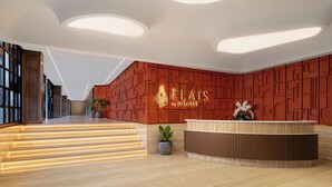 En modern hotellobby med en receptionsdisk, en trappa och en vägg med ett geometriskt mönster.
