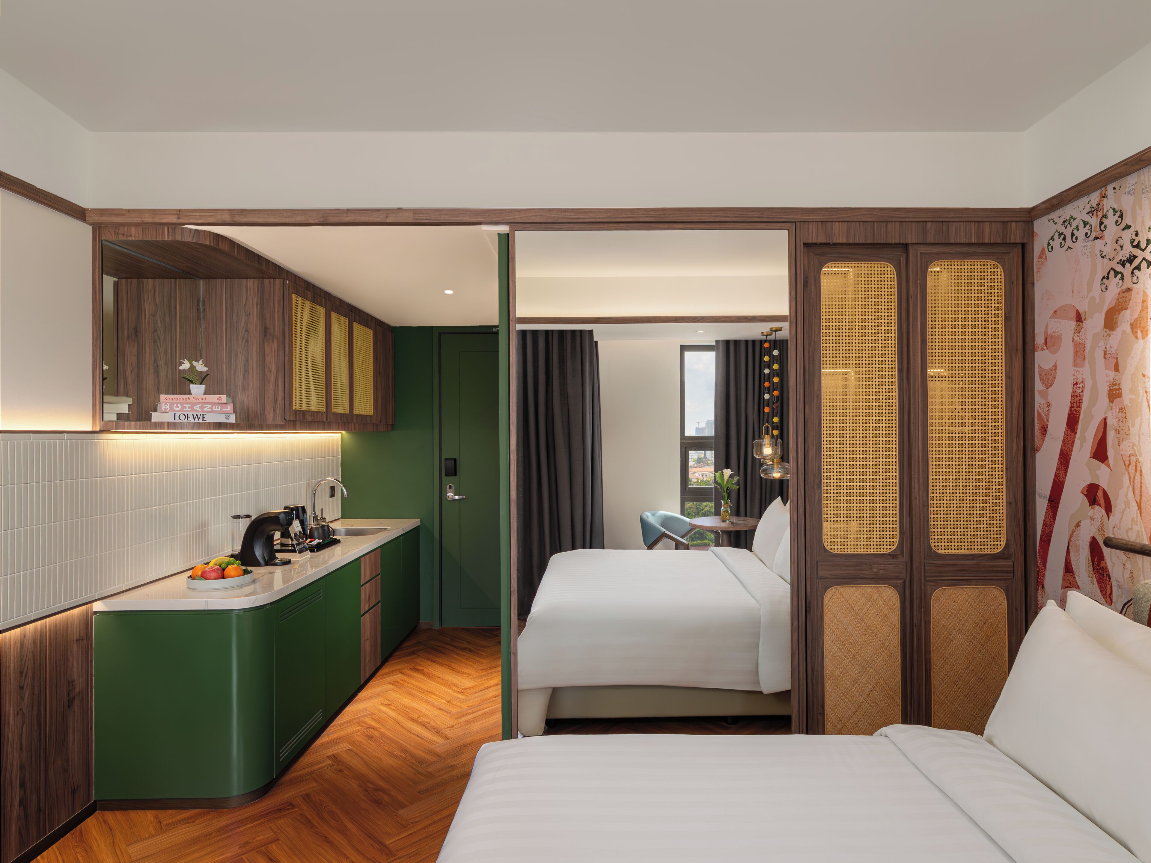 A hotel room with a kitchenette, a bed, a small table, and a view of the city.