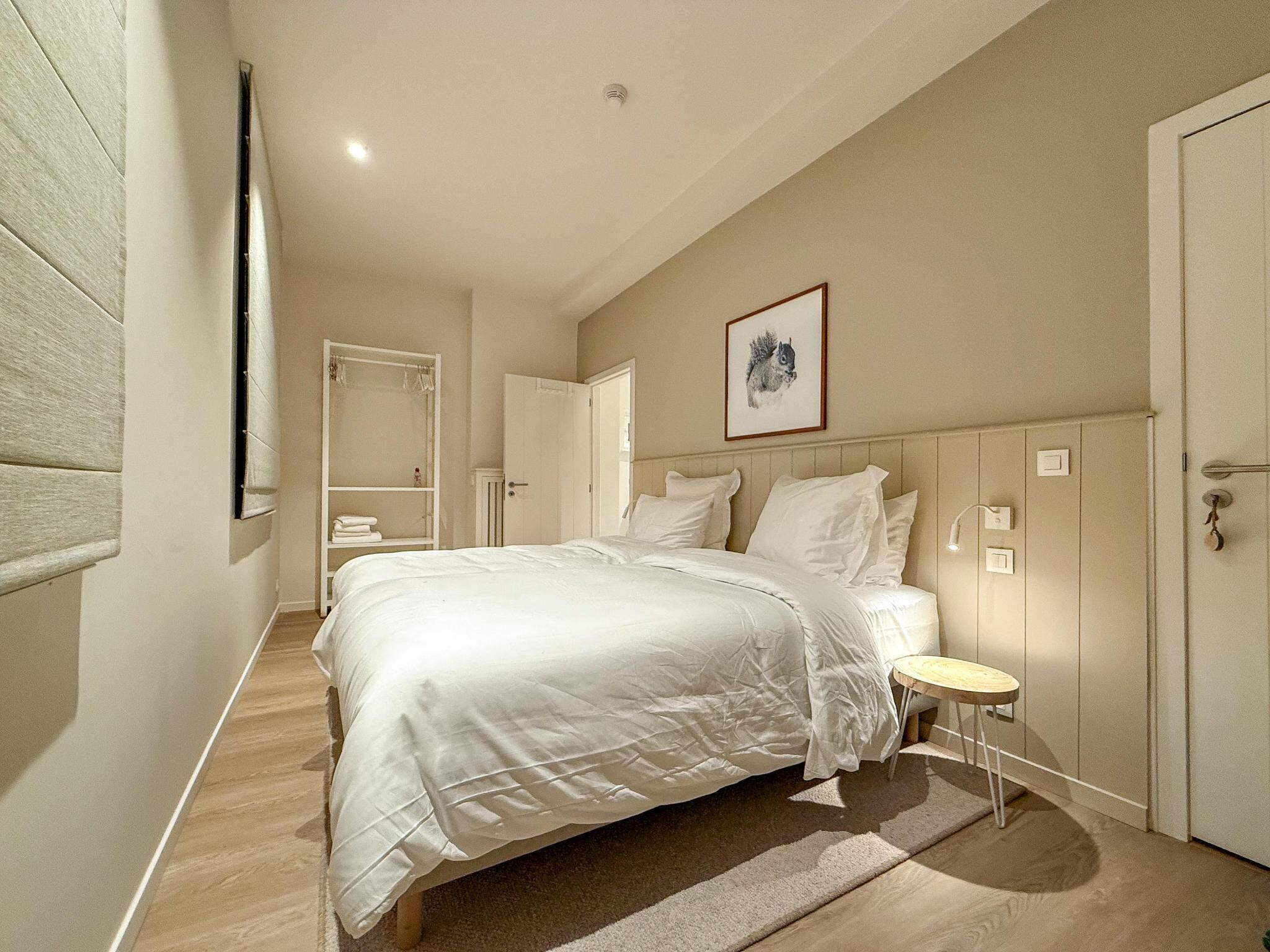 Een slaapkamer met een groot bed, een nachtkastje, een kledingkast en een deur.