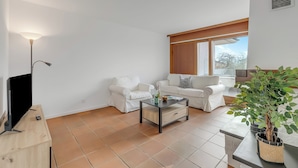 Una sala de estar con un conjunto de sofá, una mesa de centro, un televisor y una planta en maceta.