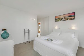 Ein Schlafzimmer in Weiß mit Bett, einem Bild, einer Vase und einer Heizung.