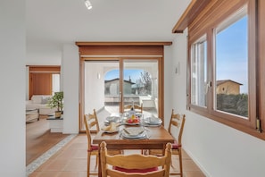 Un coin repas avec une table dressée pour quatre personnes, un canapé et une plante en pot en arrière-plan.