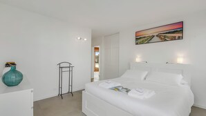 A white bedroom with a bed, a painting, a vase, and a radiator. - Casa Di Bea - Lugano 1BR With Terrace & Parking (Lugano)