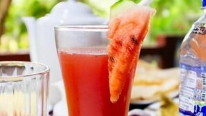 Un grand verre contenant une boisson rouge, une paille et une tranche de fruit posée sur le bord.