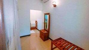Un couloir avec un banc en bois, un miroir et une porte donnant sur une autre pièce.