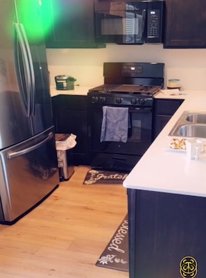 Eine Küche mit Kühlschrank, Herd, Backofen, Mikrowelle und Spüle.