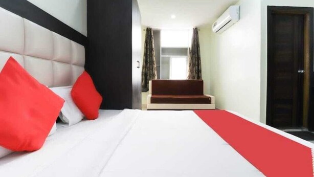 A hotel room with a bed, a red carpet, a sofa, and a door. - Hotel Heritage Villa By MNG Rooms (Kanpur)