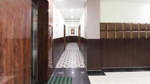A hotel lobby with a checkered floor, a wooden reception desk, and a padded wall. - Hotel Heritage Villa By MNG Rooms (Kanpur)