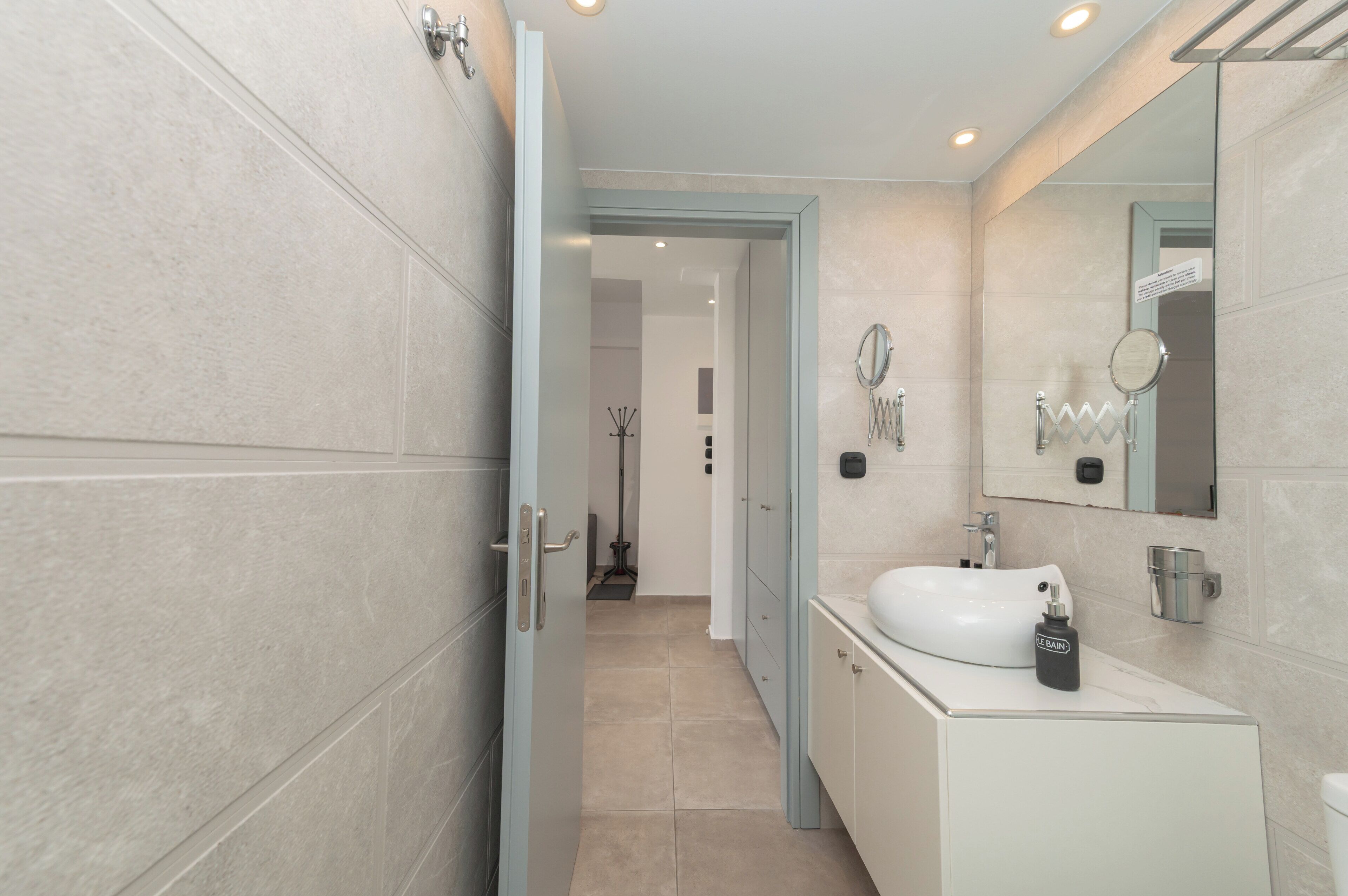 A modern bathroom with a white sink, mirror, and light blue cabinets.