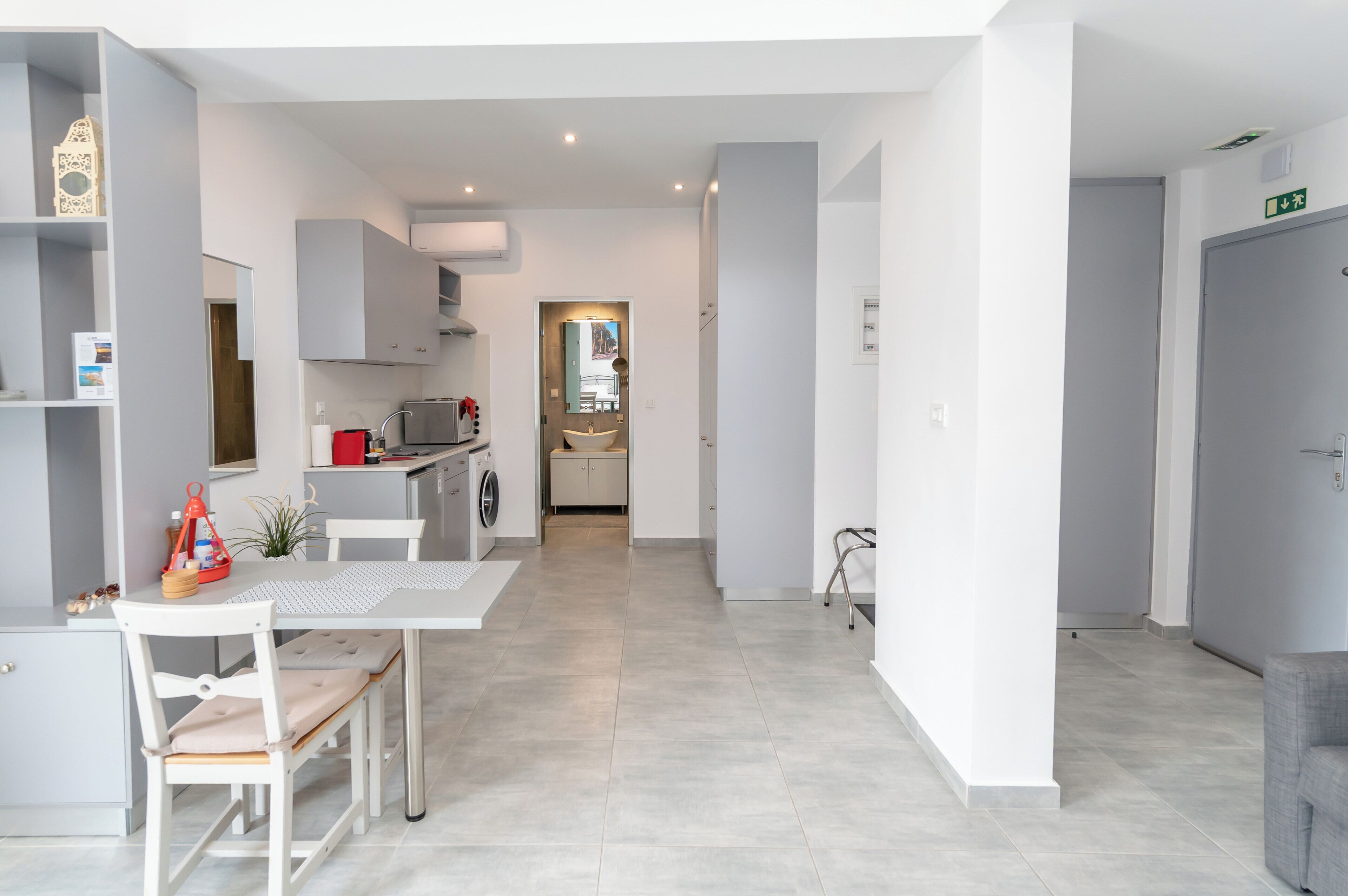 A modern kitchen with a dining area, a washing machine, and a small table with chairs.