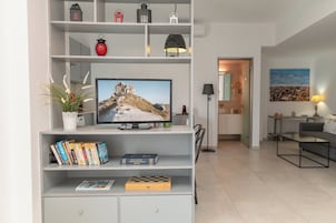 Una sala de estar moderna con televisor, libros y objetos decorativos en estanterías.