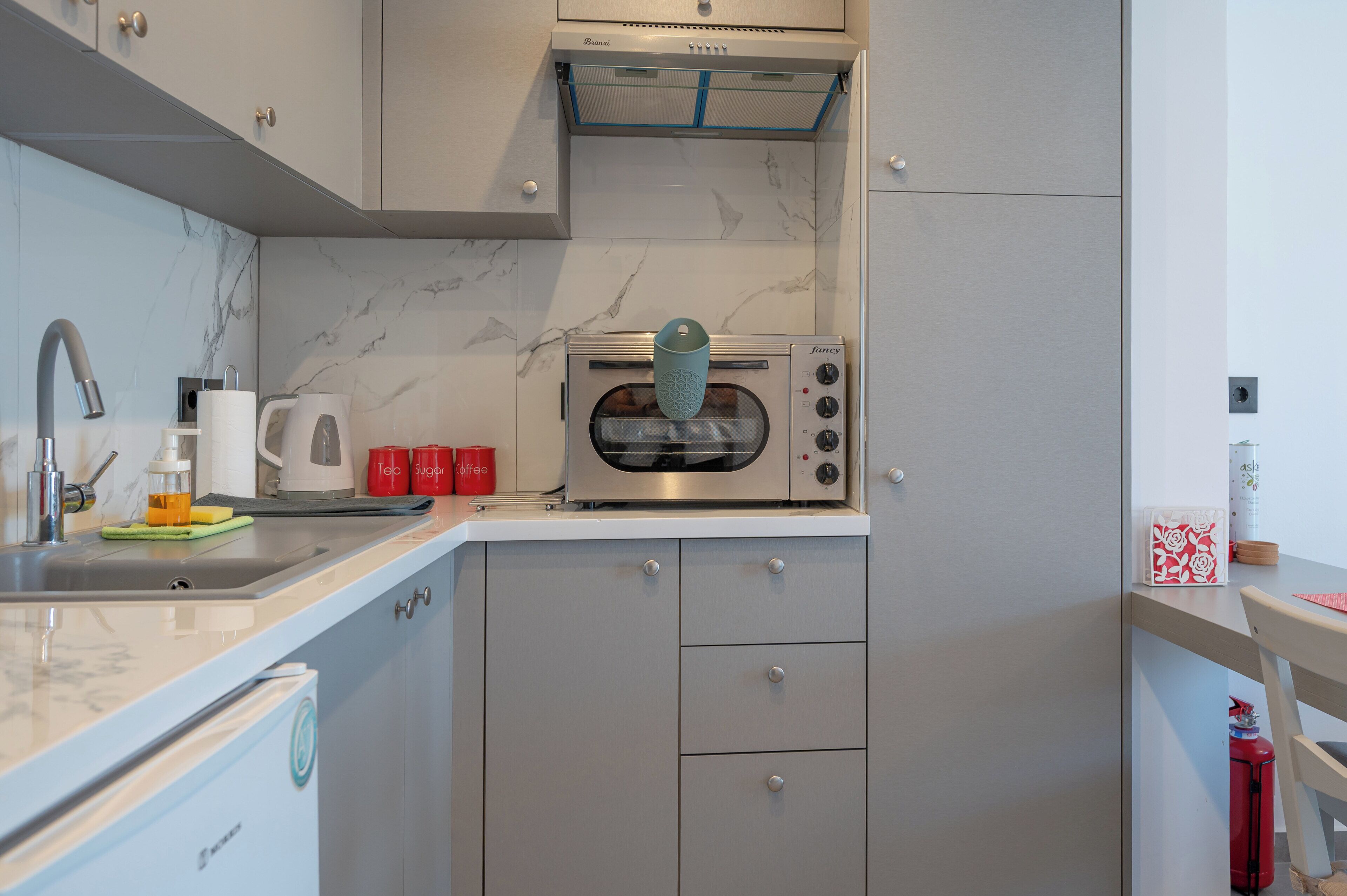 A kitchen with a built-in toaster oven, a sink, and a coffee maker.