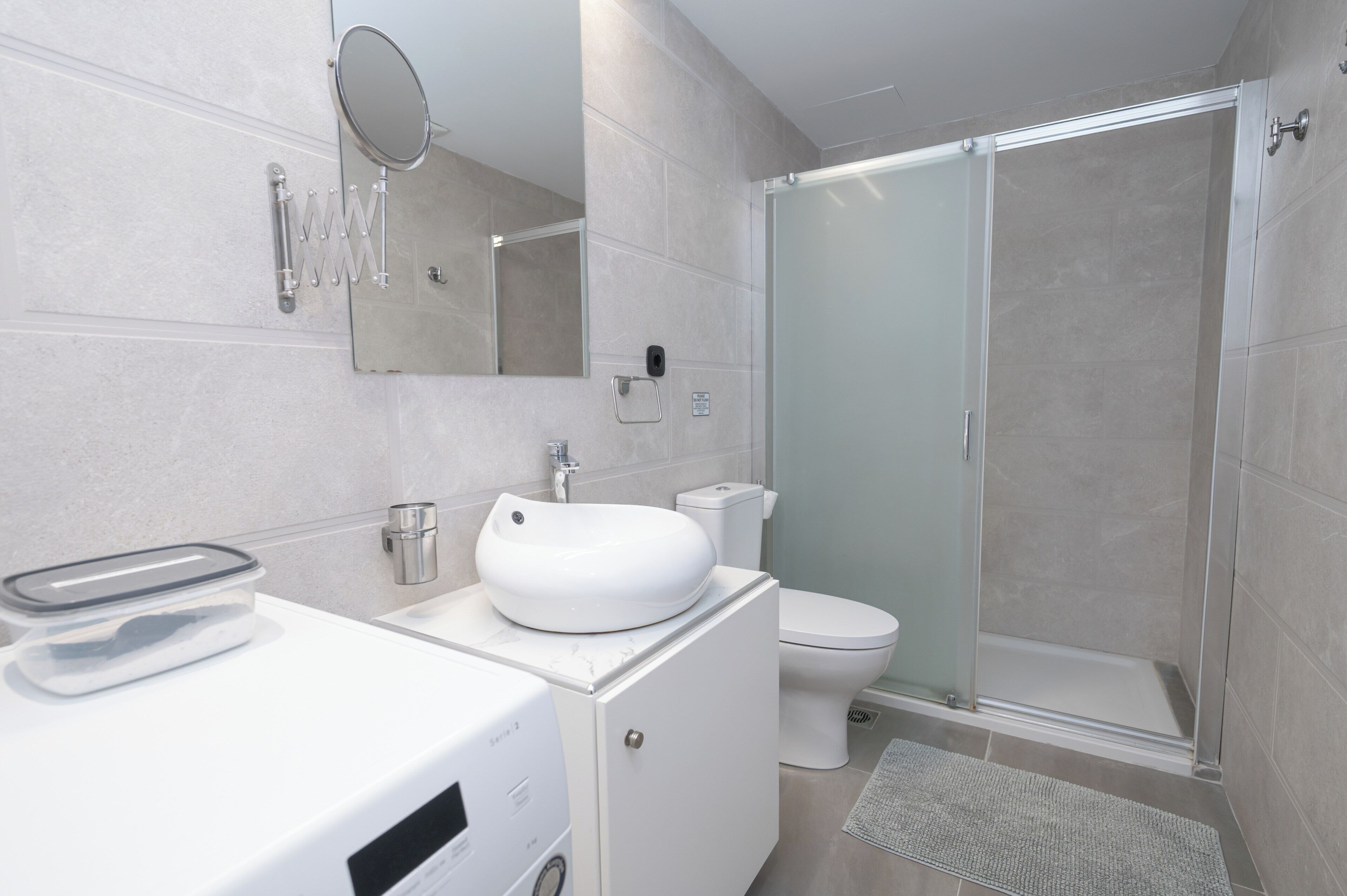 A modern bathroom with a white sink, toilet, and glass shower enclosure.