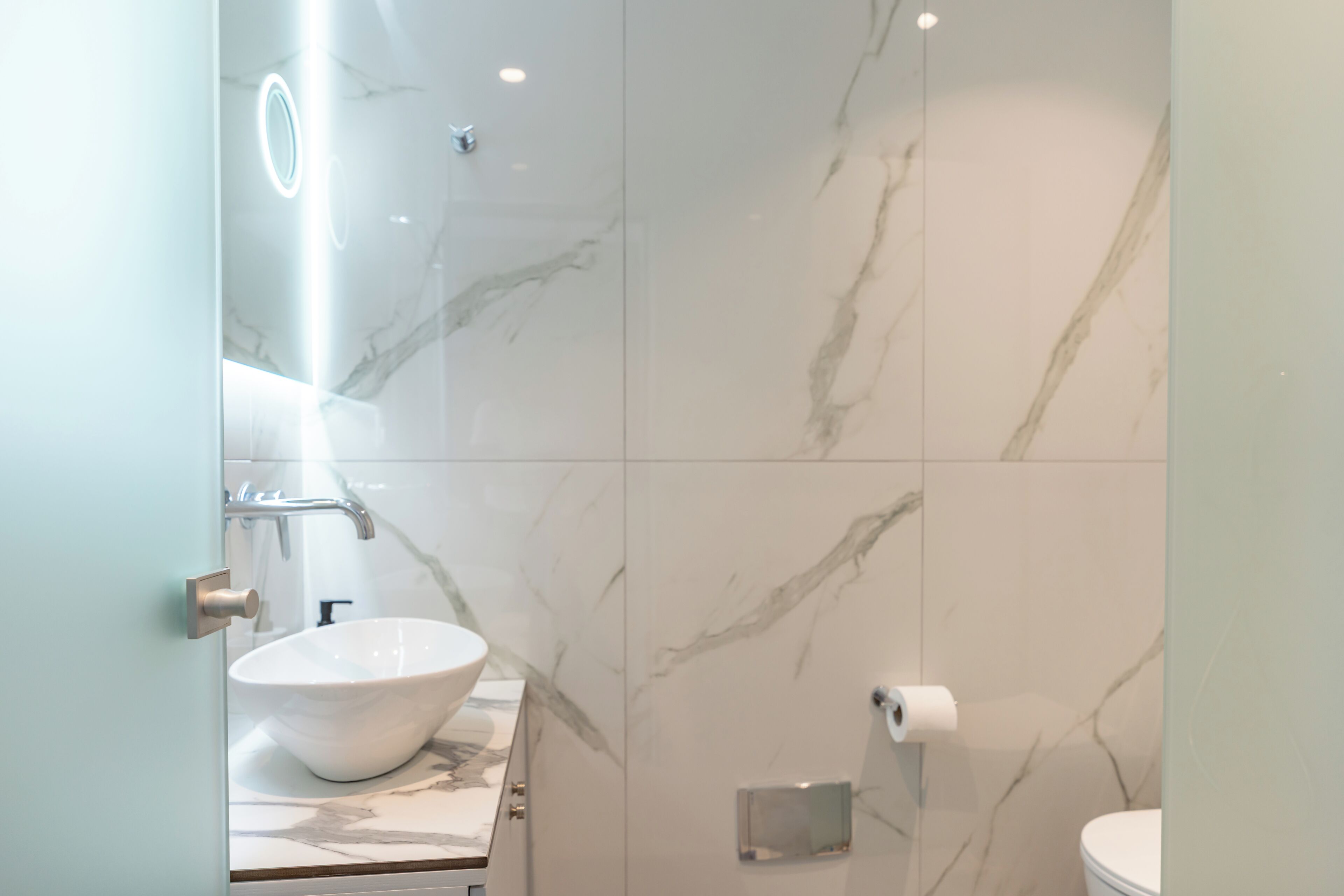 Un baño con lavamanos de mármol, inodoro y cabina de ducha de vidrio.