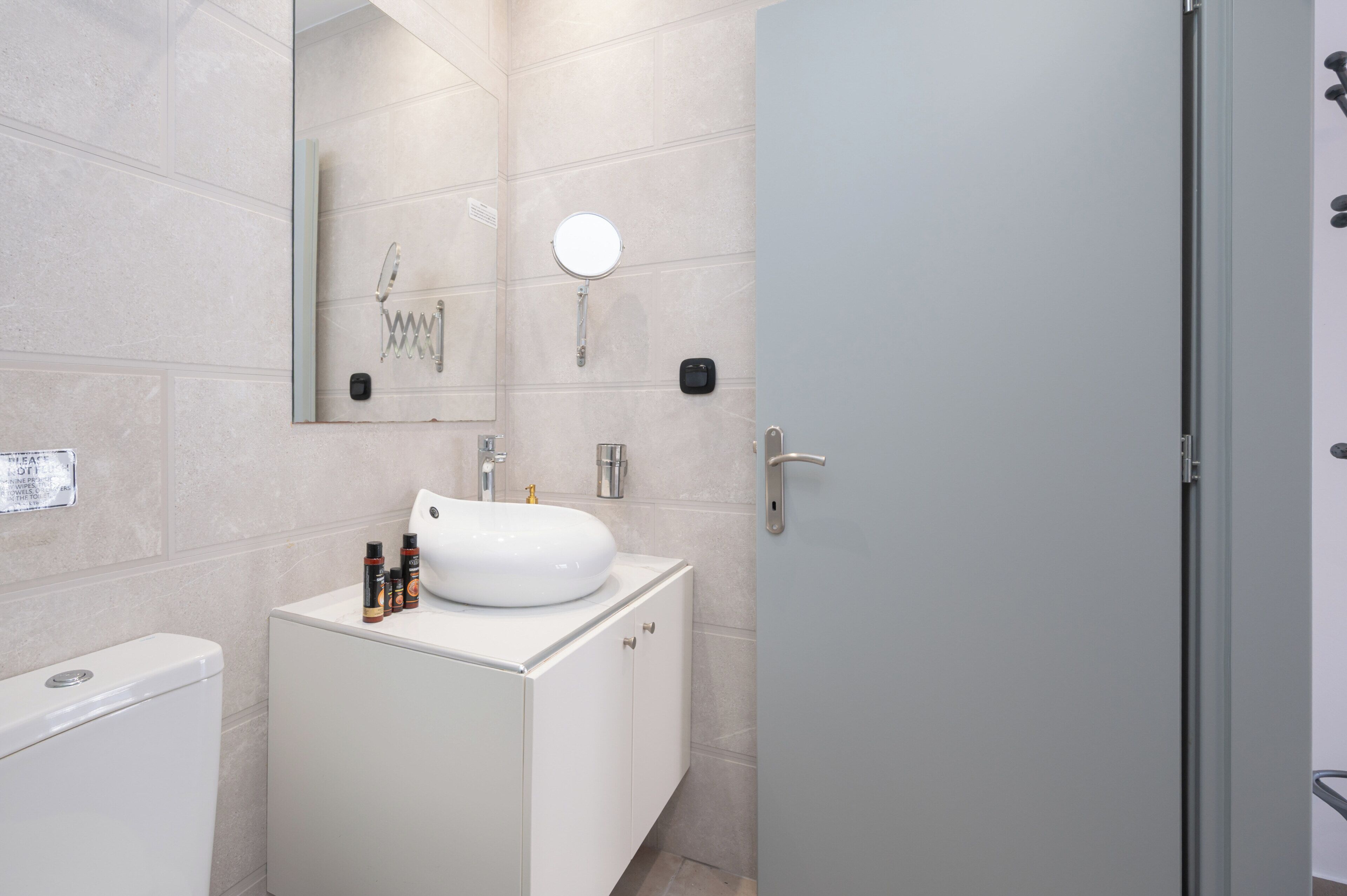 A modern bathroom with a white sink, mirror, and shower.