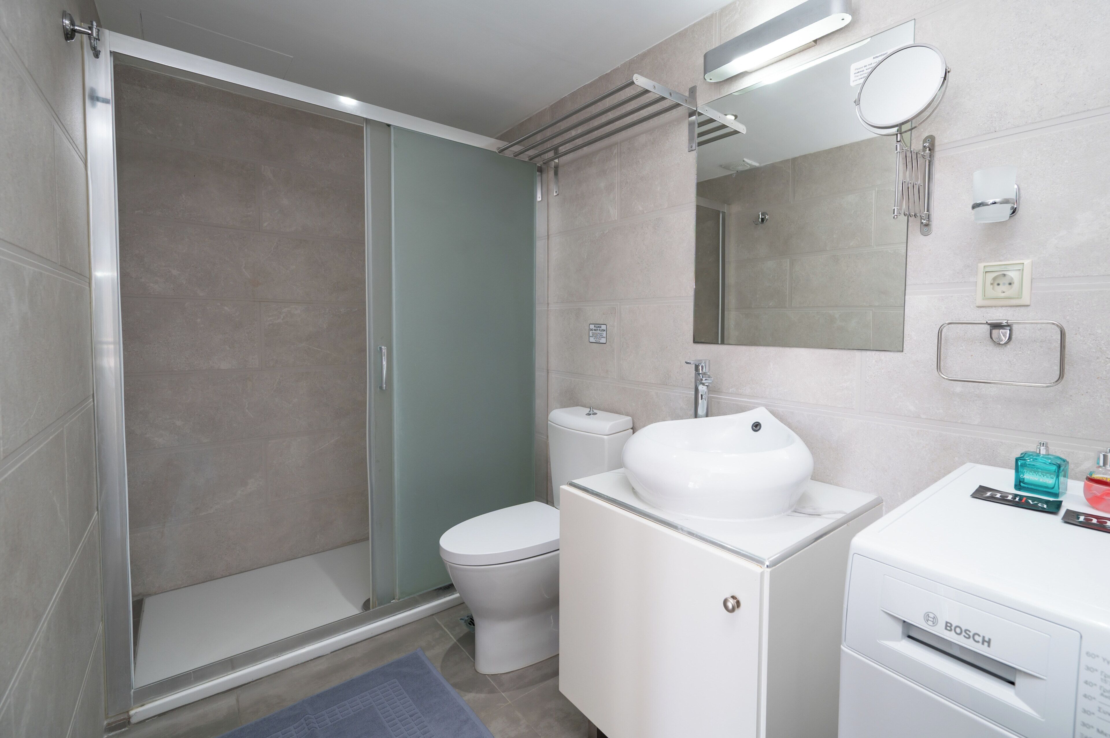 A bathroom with a shower, toilet, sink, and mirror.