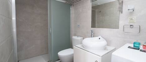 A bathroom with a shower, toilet, sink, and mirror.