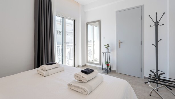 A hotel room with a bed, a coat rack, a door, and a window. - Milva Apartments (Kos)
