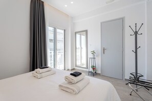 A hotel room with a bed, a coat rack, a door, and a window. - Milva Apartments (Kos)