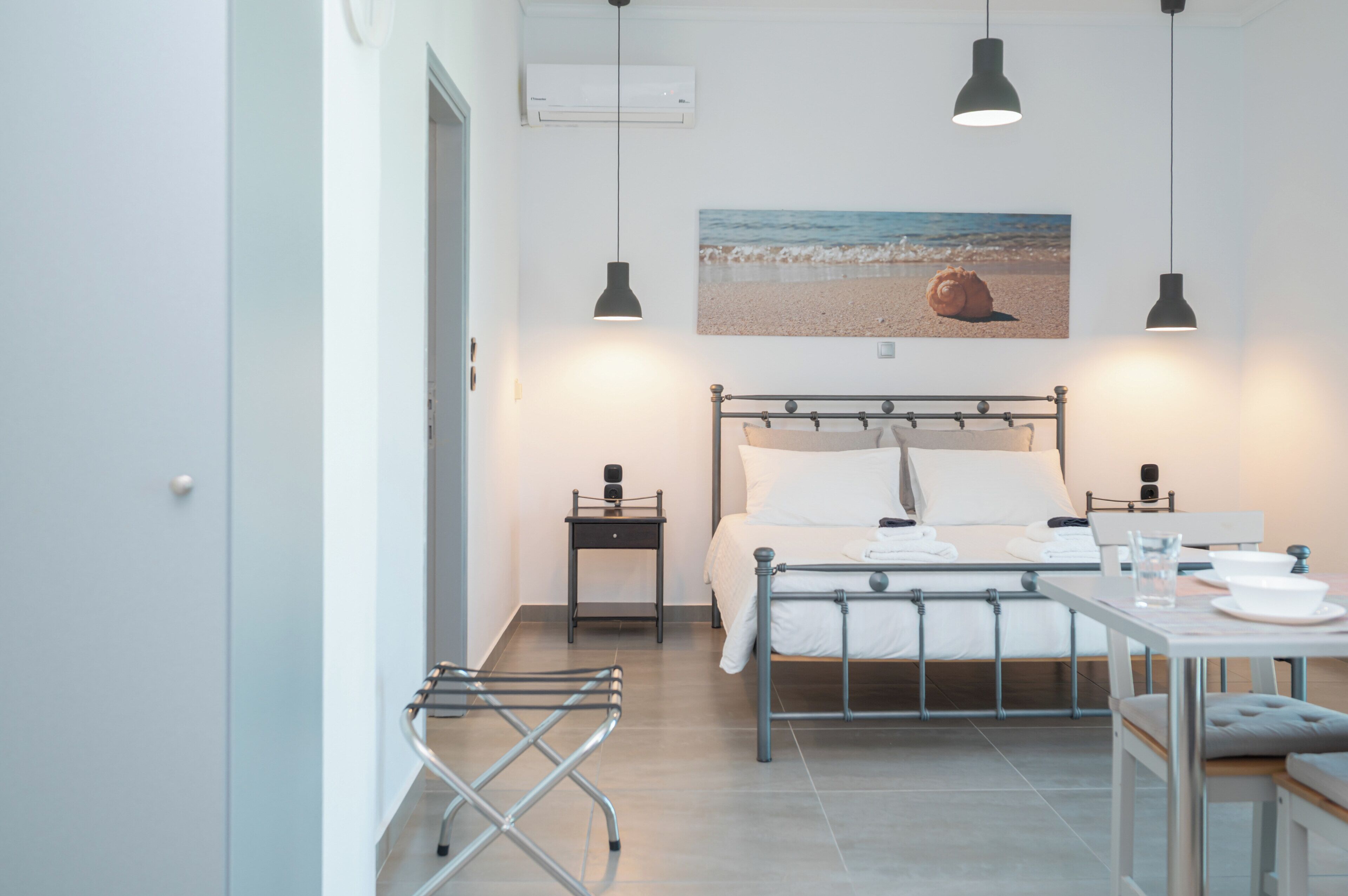 Ein Schlafzimmer mit Bett, Nachttischen, Schreibtisch und Stuhl. An der Wand hängt ein Bild mit einer Strandansicht.