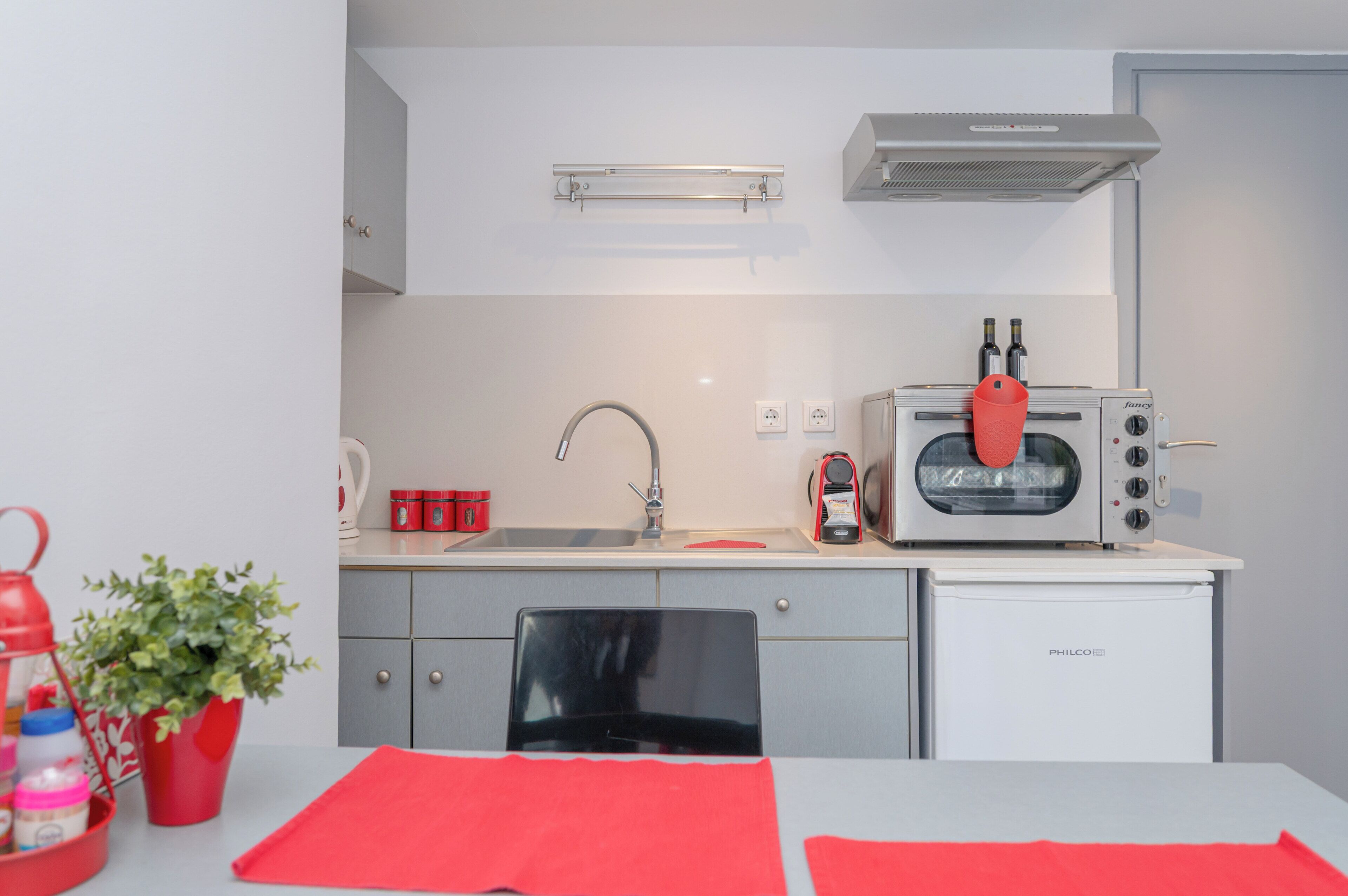 A compact kitchenette with a microwave, toaster, sink, and a small refrigerator.