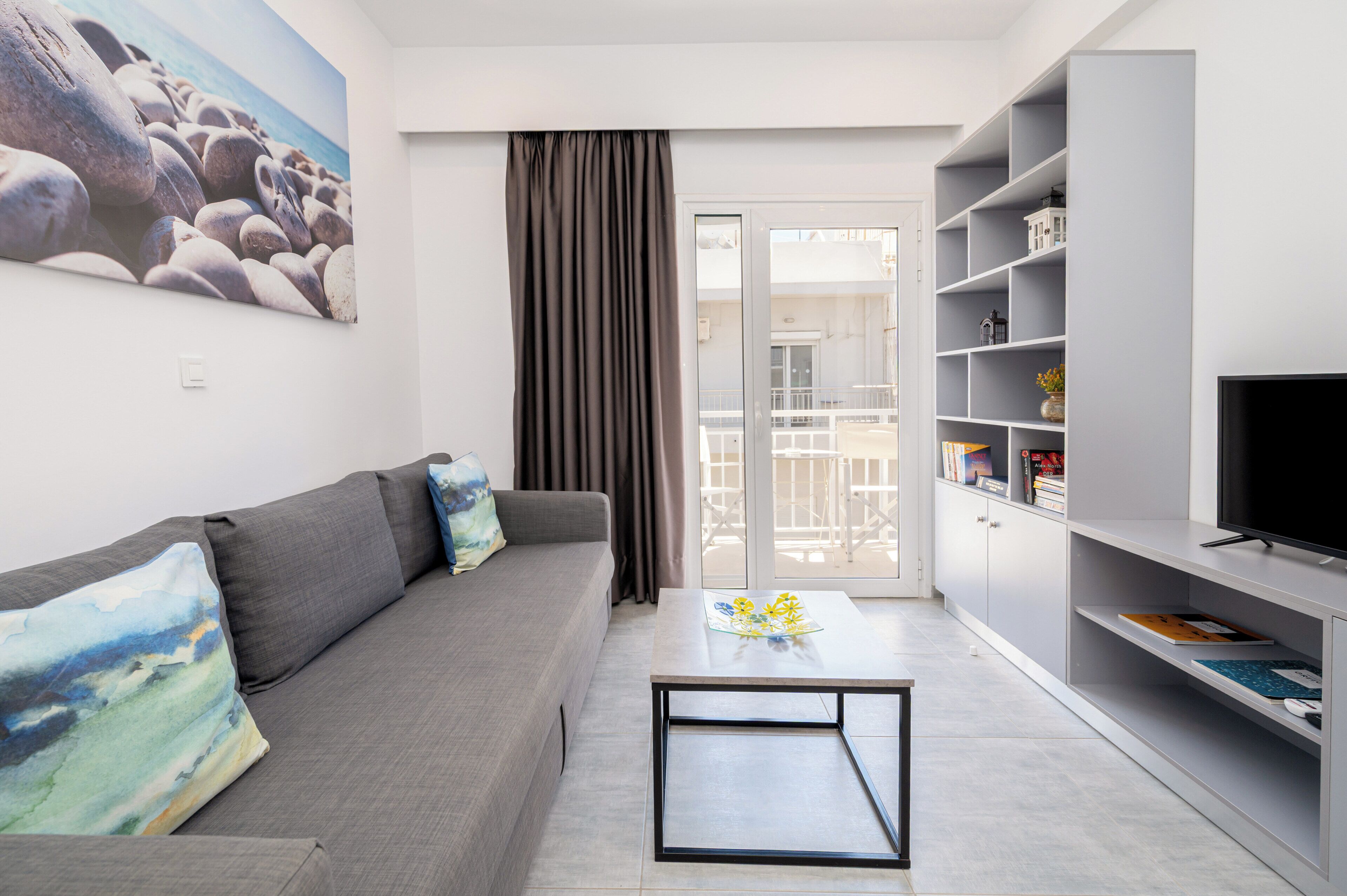 A modern living room with a grey sofa, a coffee table, and a TV on a stand.