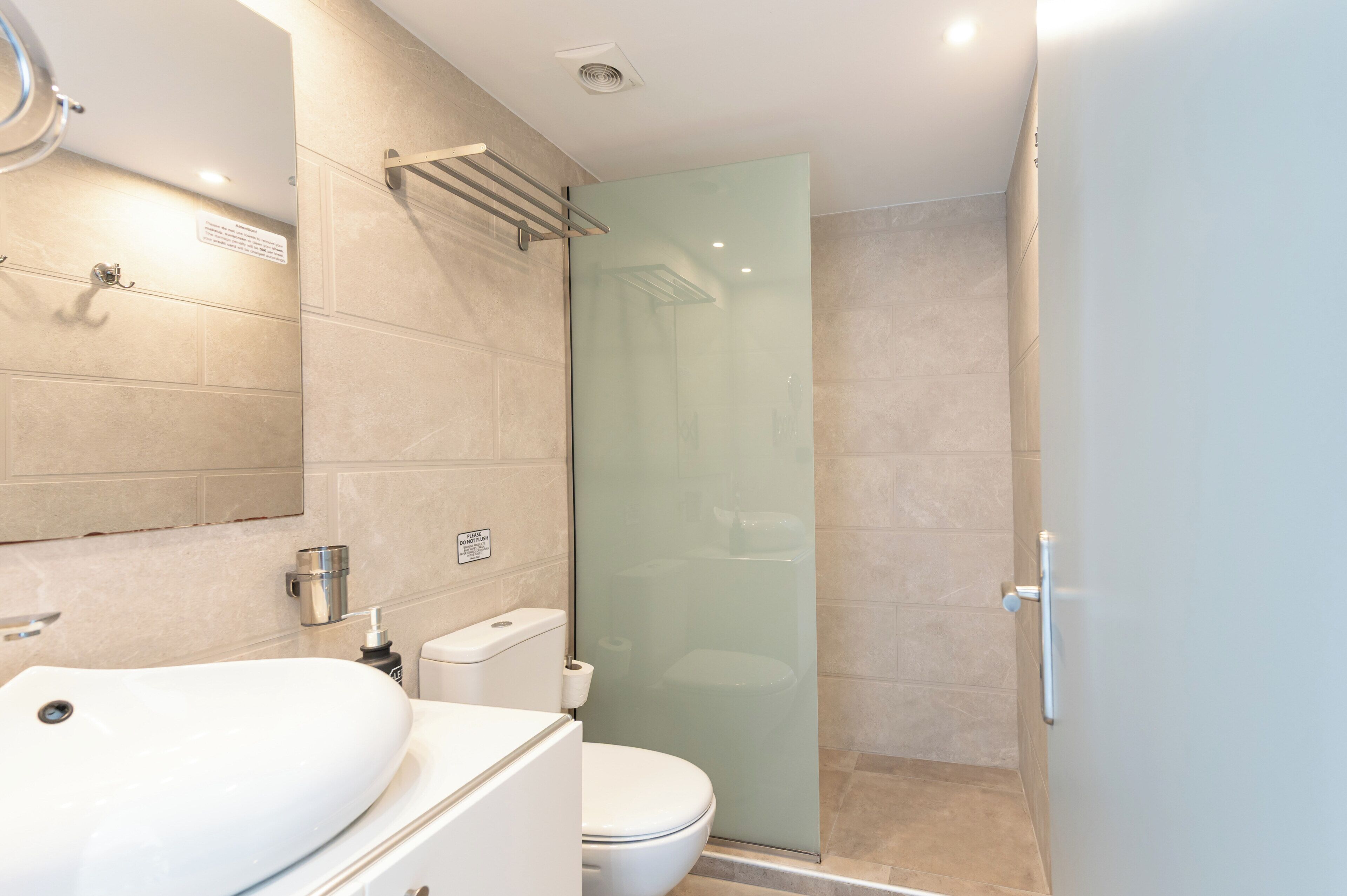 Un bagno moderno con box doccia in vetro, lavandino bianco e water.