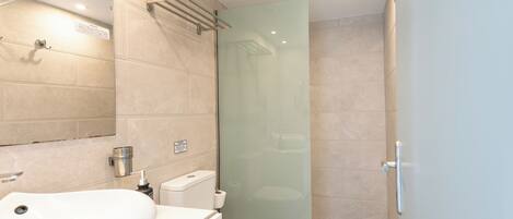 Un bagno moderno con box doccia in vetro, lavandino bianco e water.