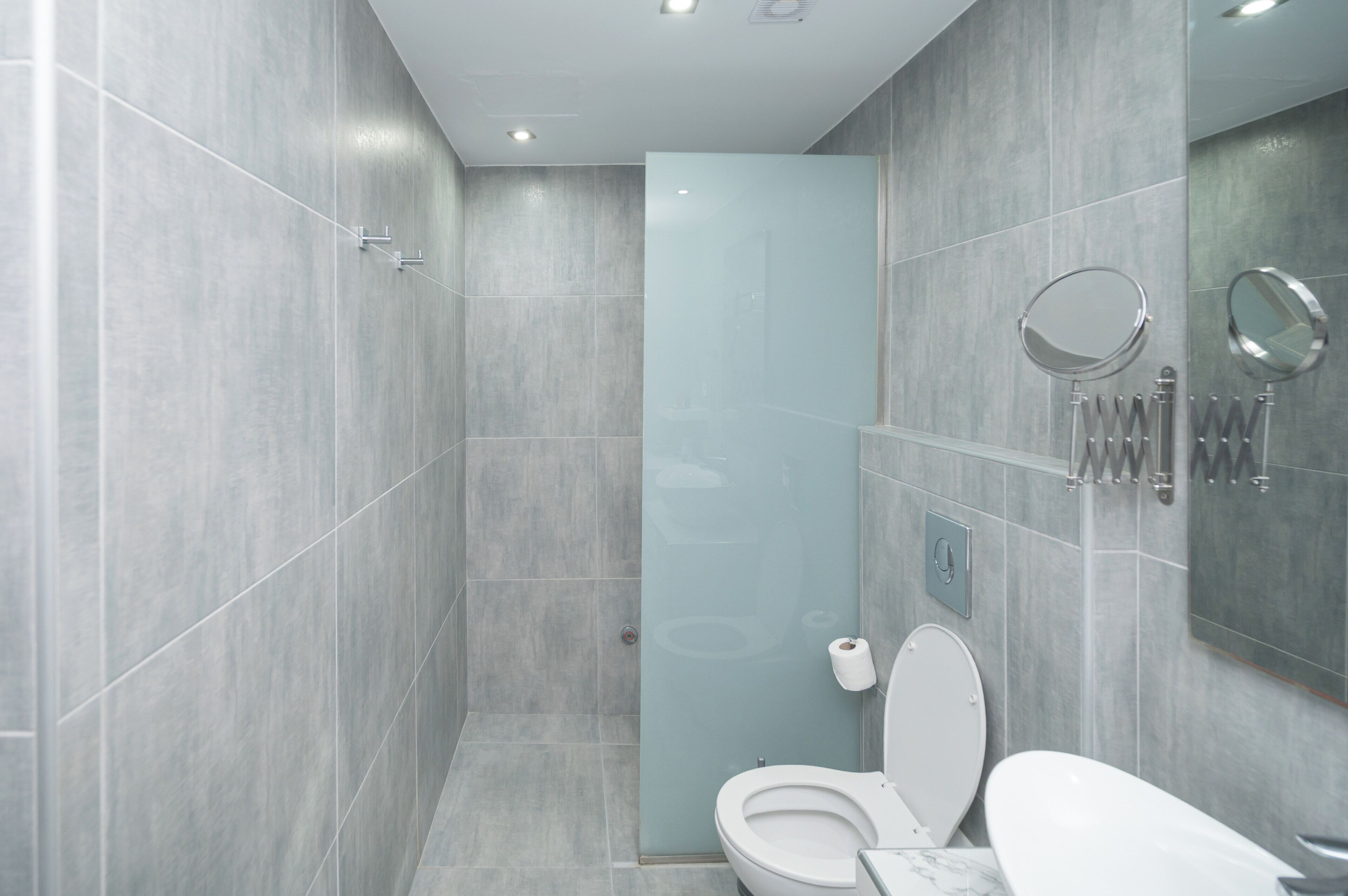 Un baño moderno con cabina de ducha de vidrio, inodoro y lavamanos de mármol.