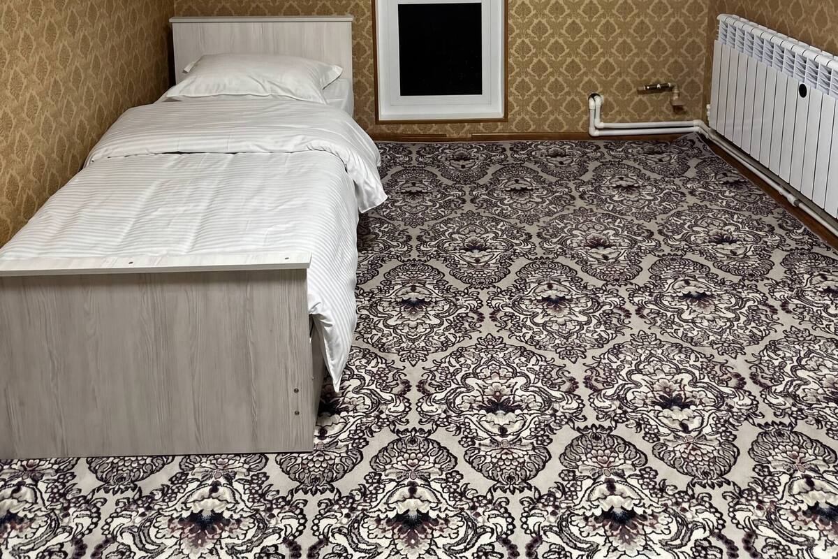 A bedroom with a bed, a radiator, and patterned wallpaper.