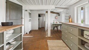 A kitchen with white cabinets, a wooden countertop, and a tiled floor. - Peace and nature in a historic holiday home (Højer)