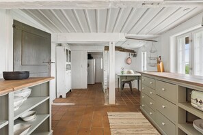 A kitchen with white cabinets, a wooden countertop, and a tiled floor.