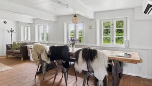 A dining area with a wooden table, chairs, and a view of greenery outside. - Peace and nature in a historic holiday home (Højer)