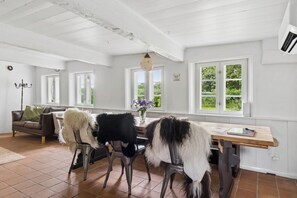 A dining area with a wooden table, chairs, and a view of greenery outside.