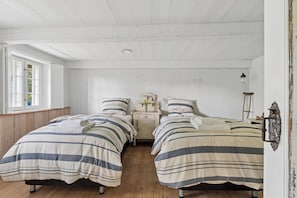 A room with two beds, a nightstand, a dresser, and a window with a view.