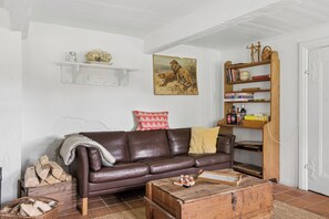 A living room with a brown leather sofa, a wooden coffee table, a bookshelf, and a painting of lions on the wall.