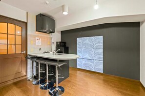 A compact kitchen with a central island, a microwave, and a black range hood. - Grace Nagahori 402 (Osaka)