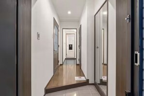 A hallway with wooden flooring, white walls, and doors on both sides. - Grace Nagahori 402 (Osaka)