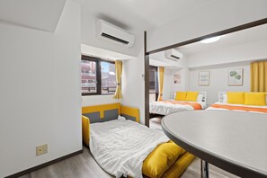 Ein Hotelzimmer mit zwei Betten, einem Esstisch und einem Fenster mit Vorhängen.