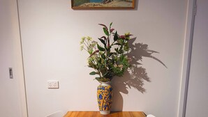 Una mesa de comedor con un jarrón de flores, dos sillas y un cuadro en la pared.